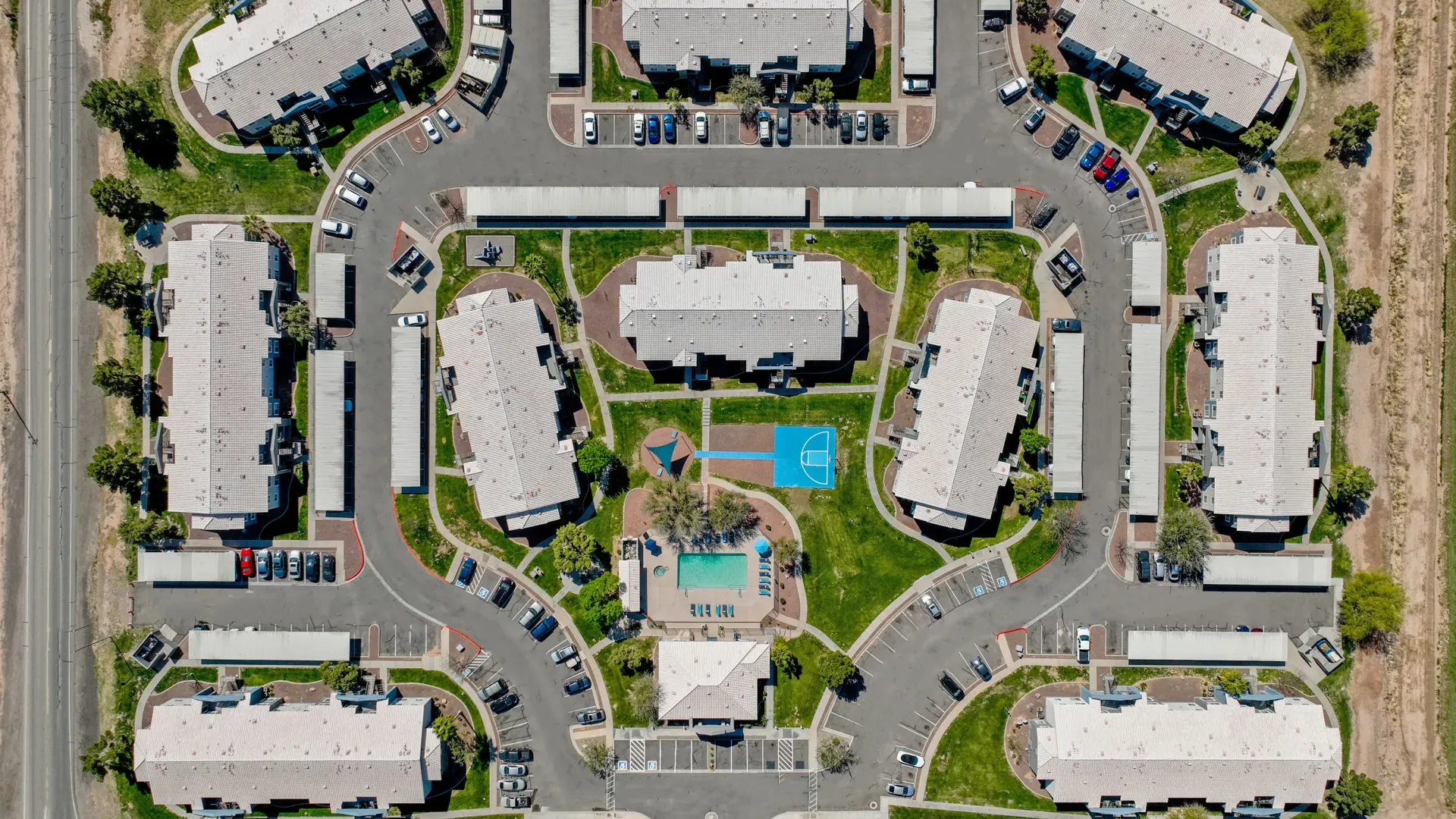 Overhead view of a robust apartment community showcasing the pool, amenities, carports, and parking spaces.