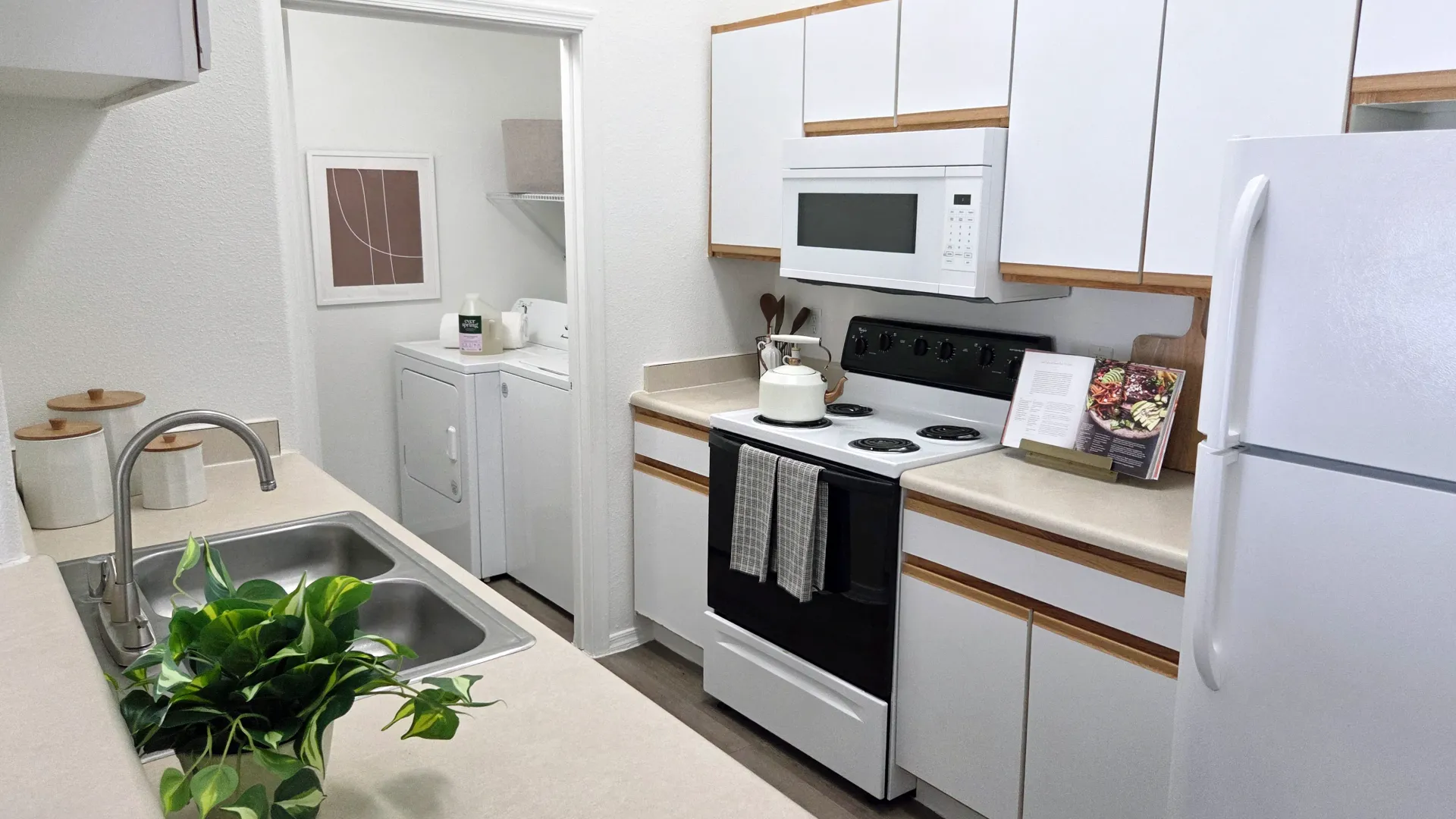 Kitchen featuring white appliances, ample cabinetry, and a separate laundry area with washer and dryer.