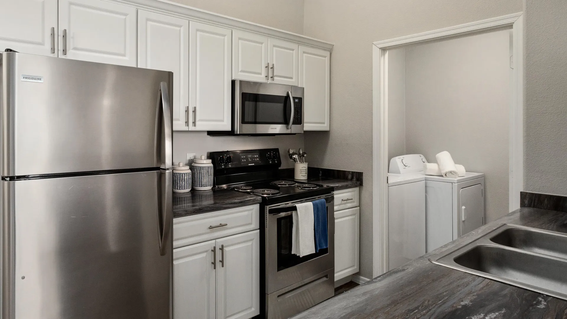 A modern kitchen with sleek white cabinetry and granite-inspired countertops.