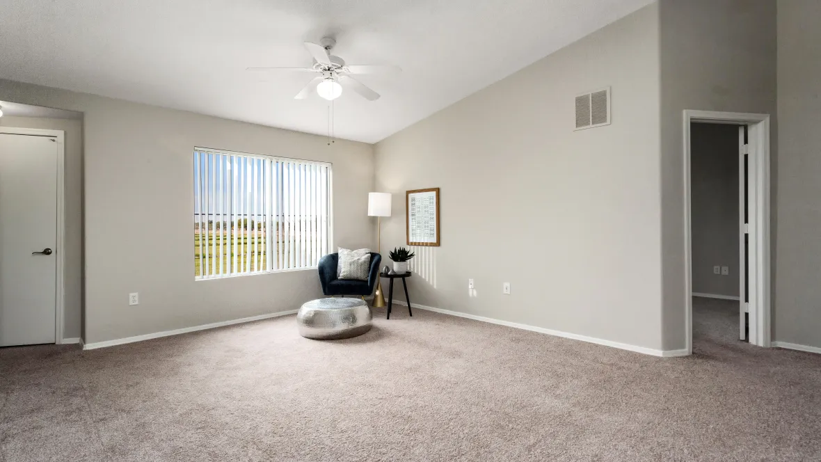 Sun-drenched living room with warm carpeting, offering an inviting view through large windows.