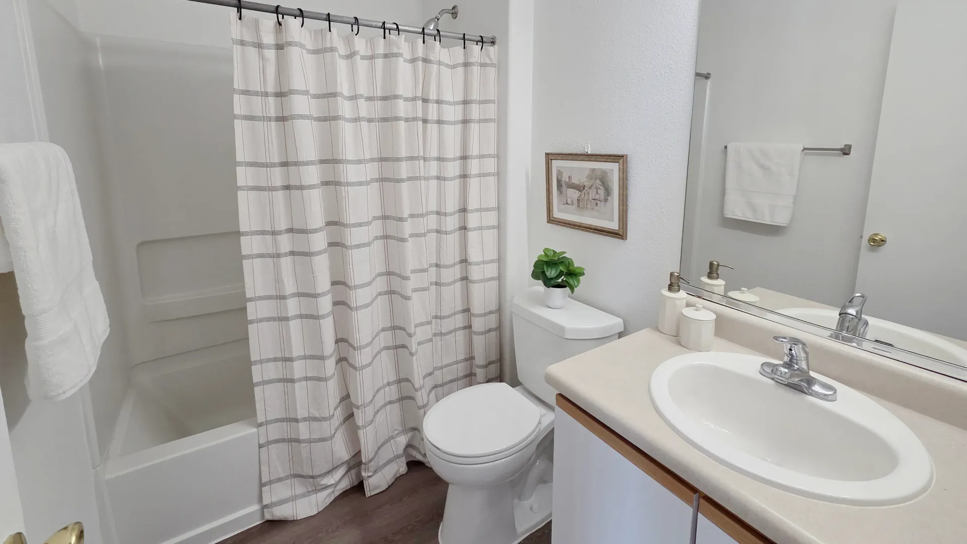 Bright bathroom with a bathtub, shower, oversized mirror, and generous countertop space.