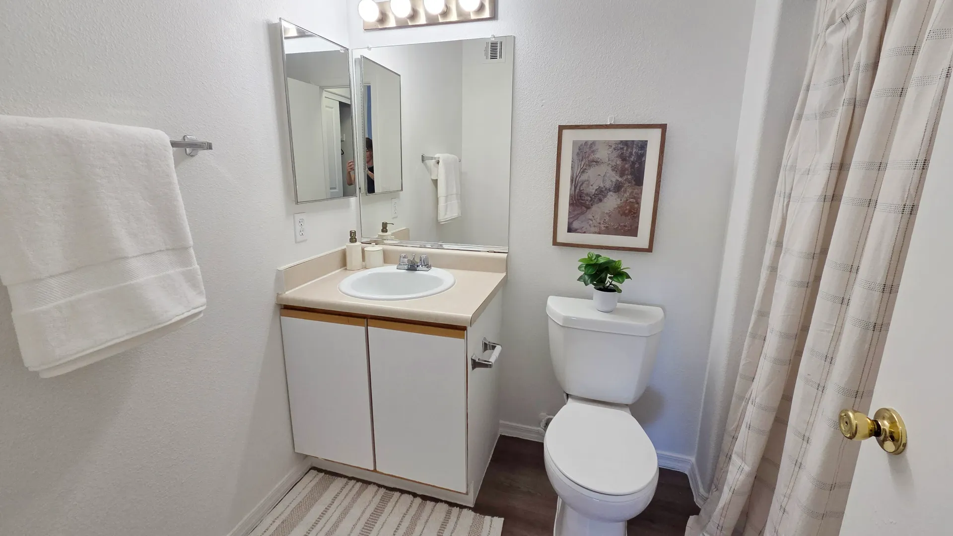 Bright apartment bathroom with a spacious vanity, oversized mirror, and shower-tub combination.