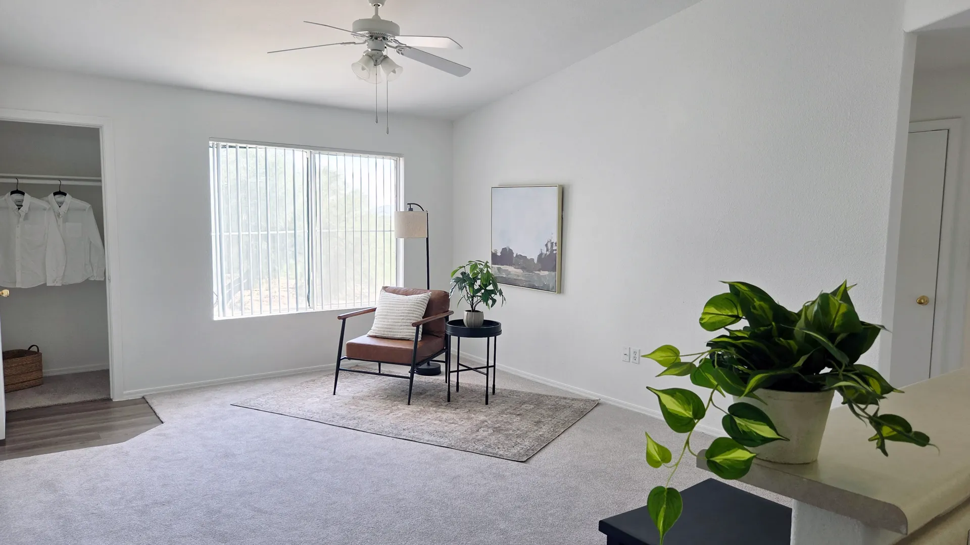 Open living room featuring a large window, neutral finishes, soft carpeting, and ample space for furnishings.