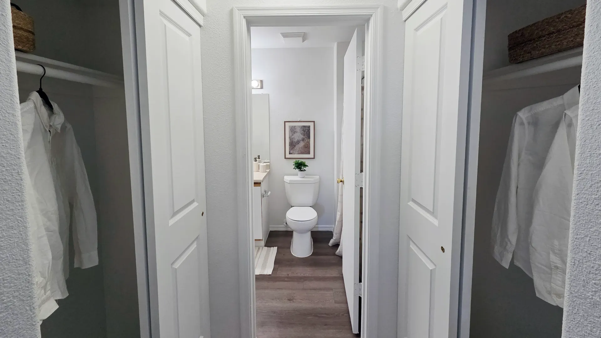 Spacious walk-through closet with dual storage areas leading to a bathroom with modern flooring and neutral finishes.