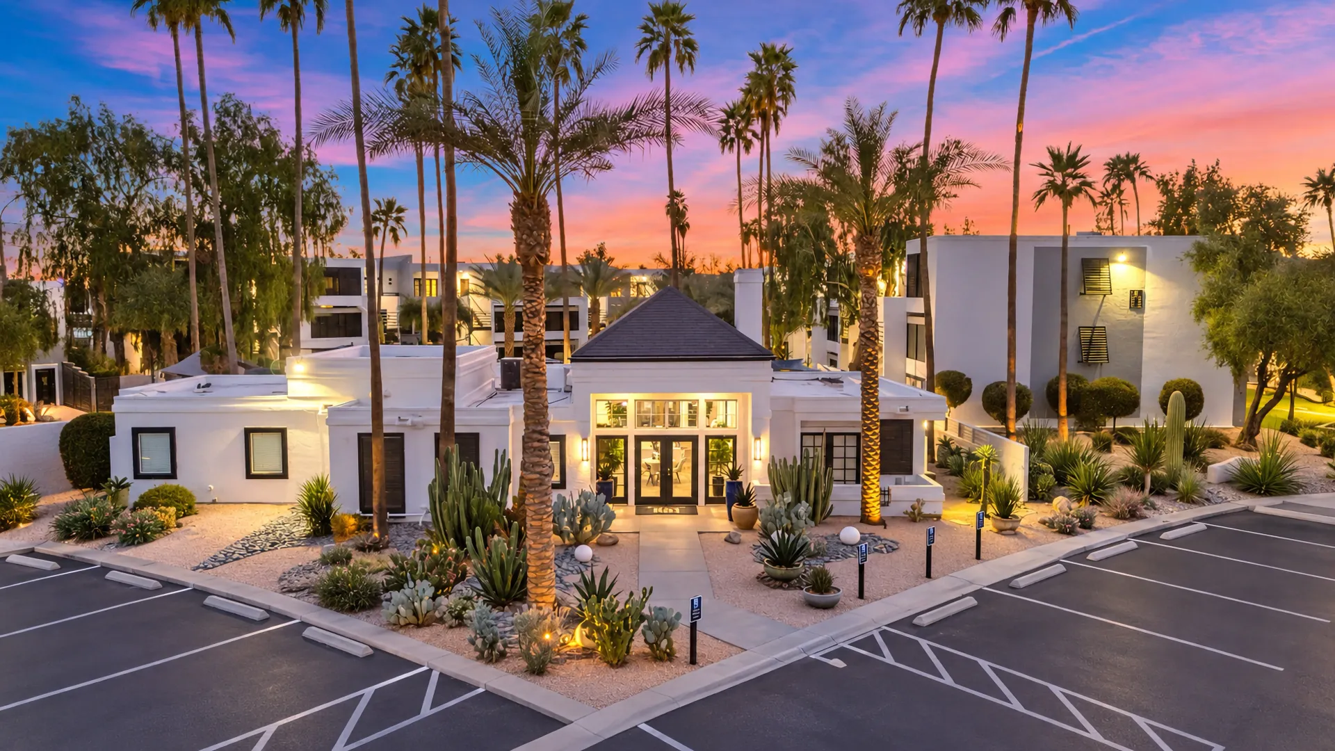 Beacon at 601 leasing office at twilight surrounded by tall palm trees, desert landscaping, and illuminated walkways.