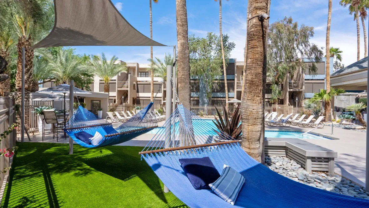 A hammock garden beneath palm trees within the pool area inviting residents to relax and rejuvenate in the serene abode. 