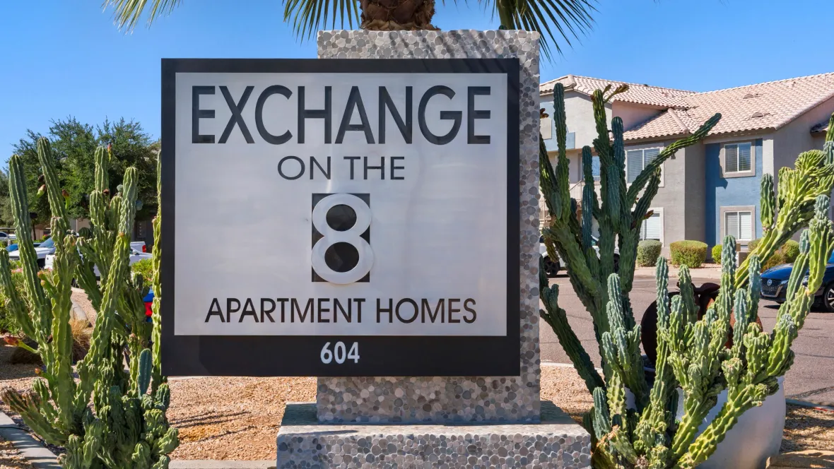 A grand entrance to Exchange on the 8, with a robust black and white sign declaring "Exchange on the 8 Apartment Homes." A joyful introduction to our amazing community and dedicated staff.