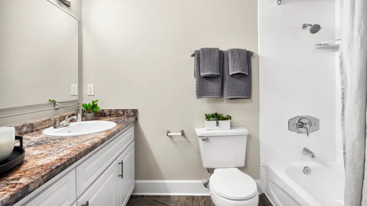 Freshly remodeled bathroom retreats with contemporary countertops, grand mirrors, wood-style flooring, and a spacious shower/tub combo for a lavish and vibrant appeal.