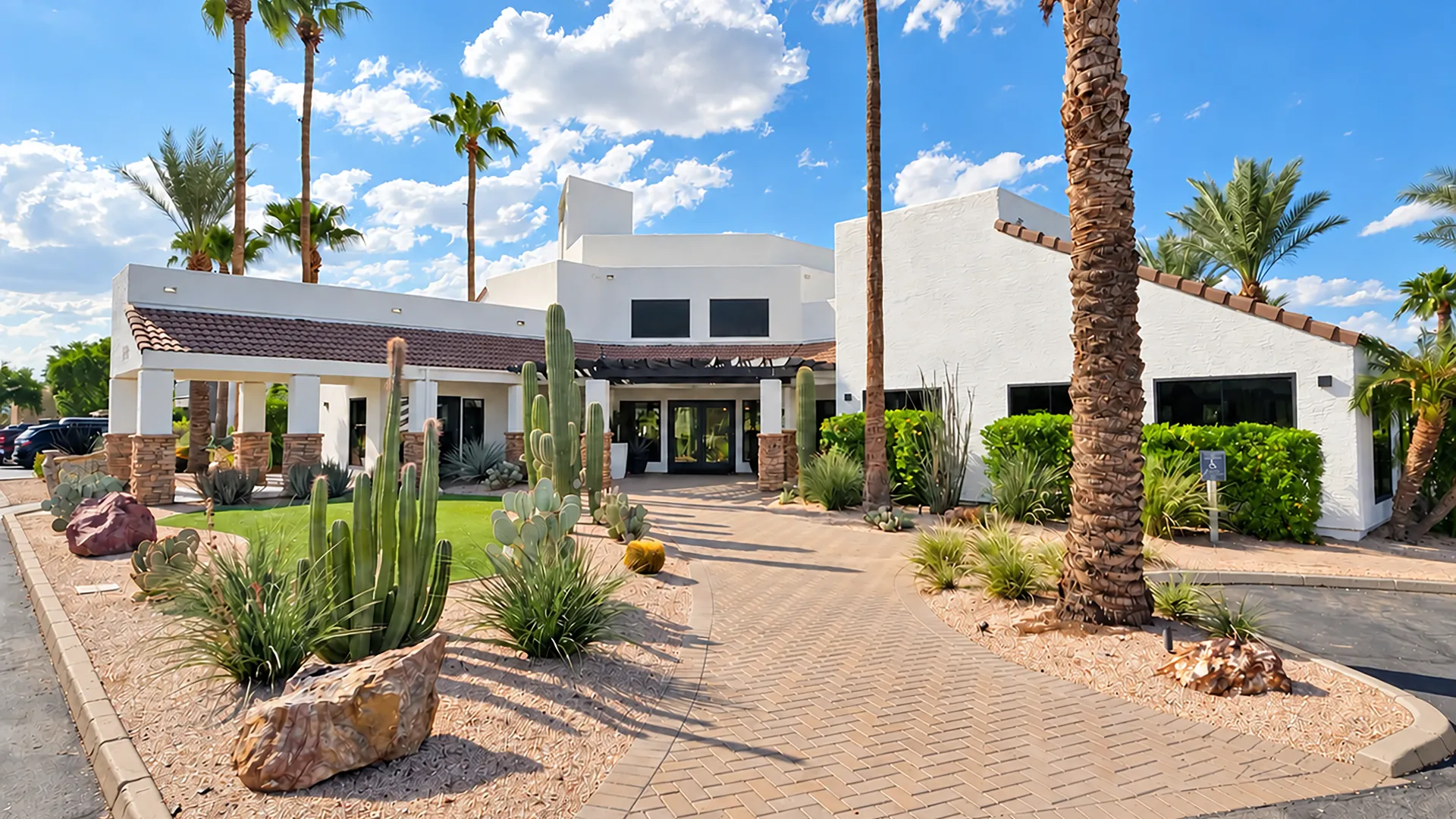 Level 550 leasing office exterior with palm trees, desert landscaping, flowering planters, and a covered entrance.