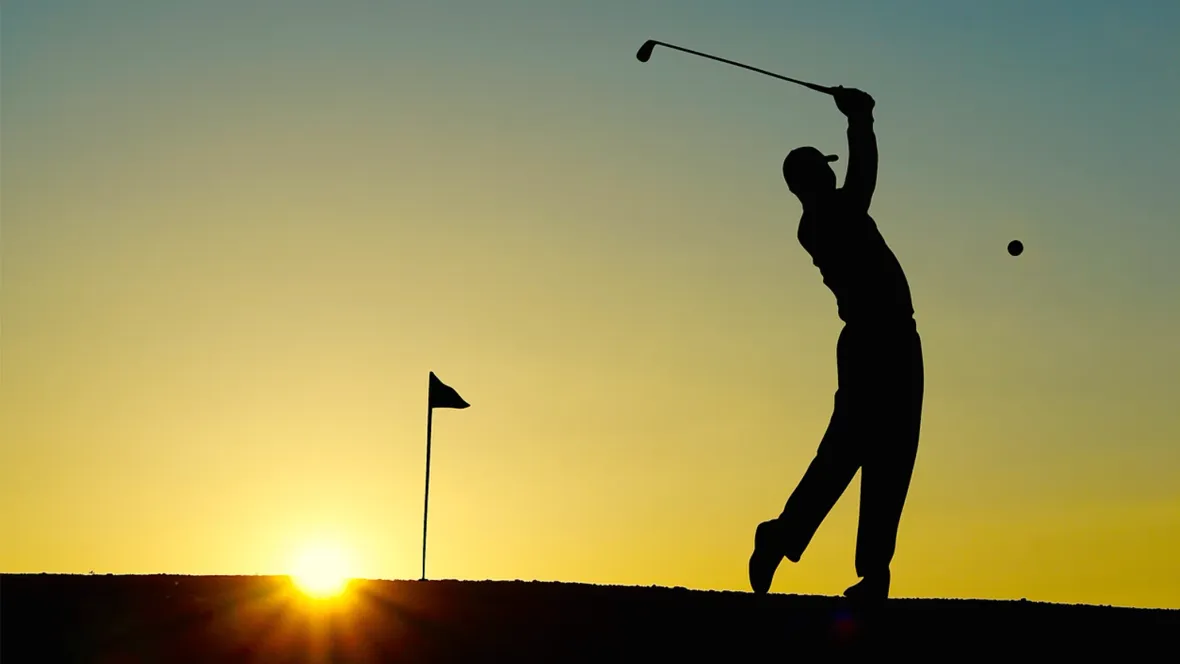 A silhouette of a golfer in the sunset