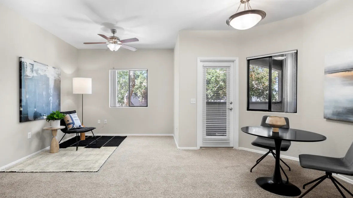 View of the seamless carpeted living and dining areas, complete with a ceiling fan and light fixture, offers the ultimate comfort.