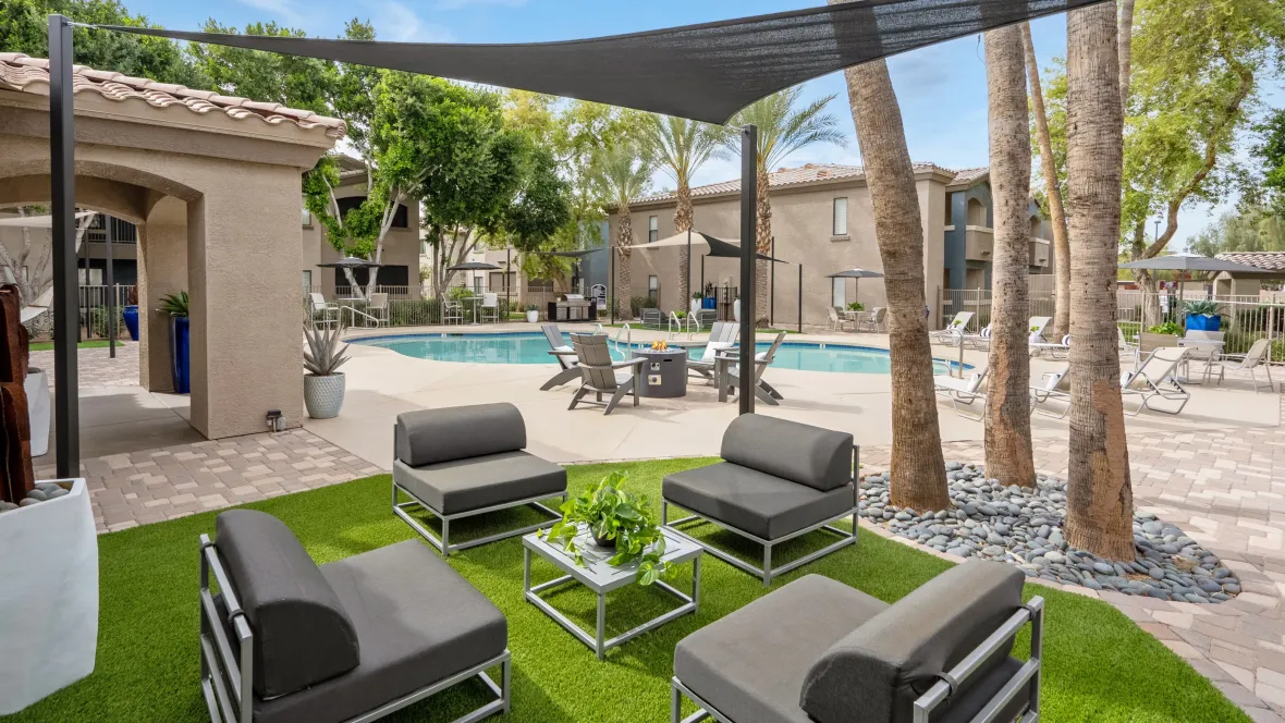 Lounge seating under sun sails with faux grass, creating a deluxe poolside ambiance.