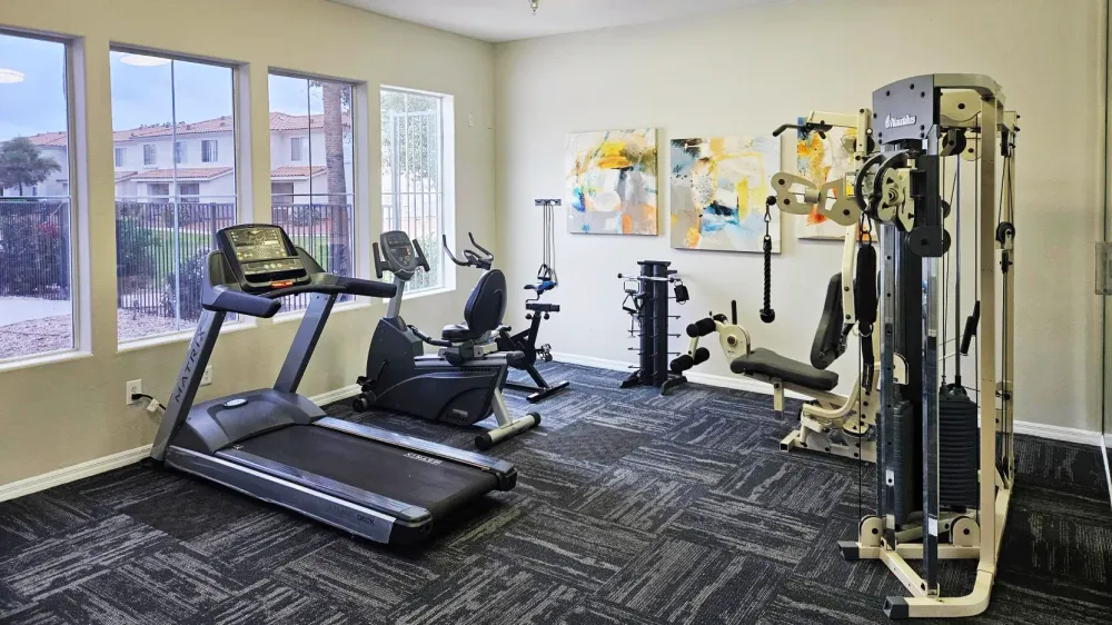 Bright on-site gym at Rancho Del Sol with treadmills, elliptical machines, and strength equipment.
