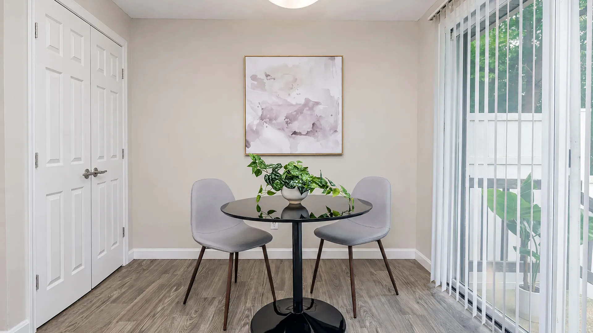 Rancho Del Sol dining area with wood-style flooring, round dining table, two chairs, and sliding glass doors leading to a private patio.