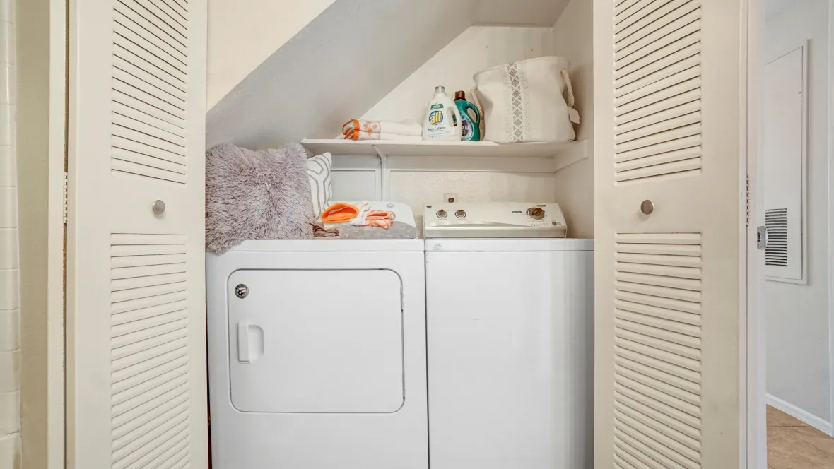 Behind double bi-fold doors reveal a cozy nook beneath stairs as the ideal space for full-size laundry units and additional storage space. 