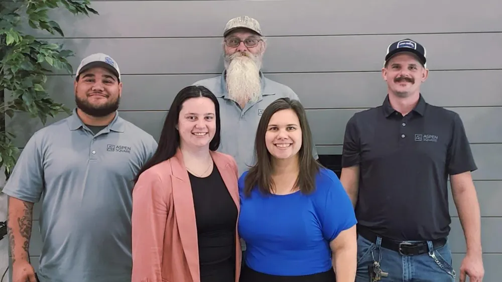 Group photo of The Avenue Apartments staff, including leasing and maintenance professionals, standing inside the leasing office.