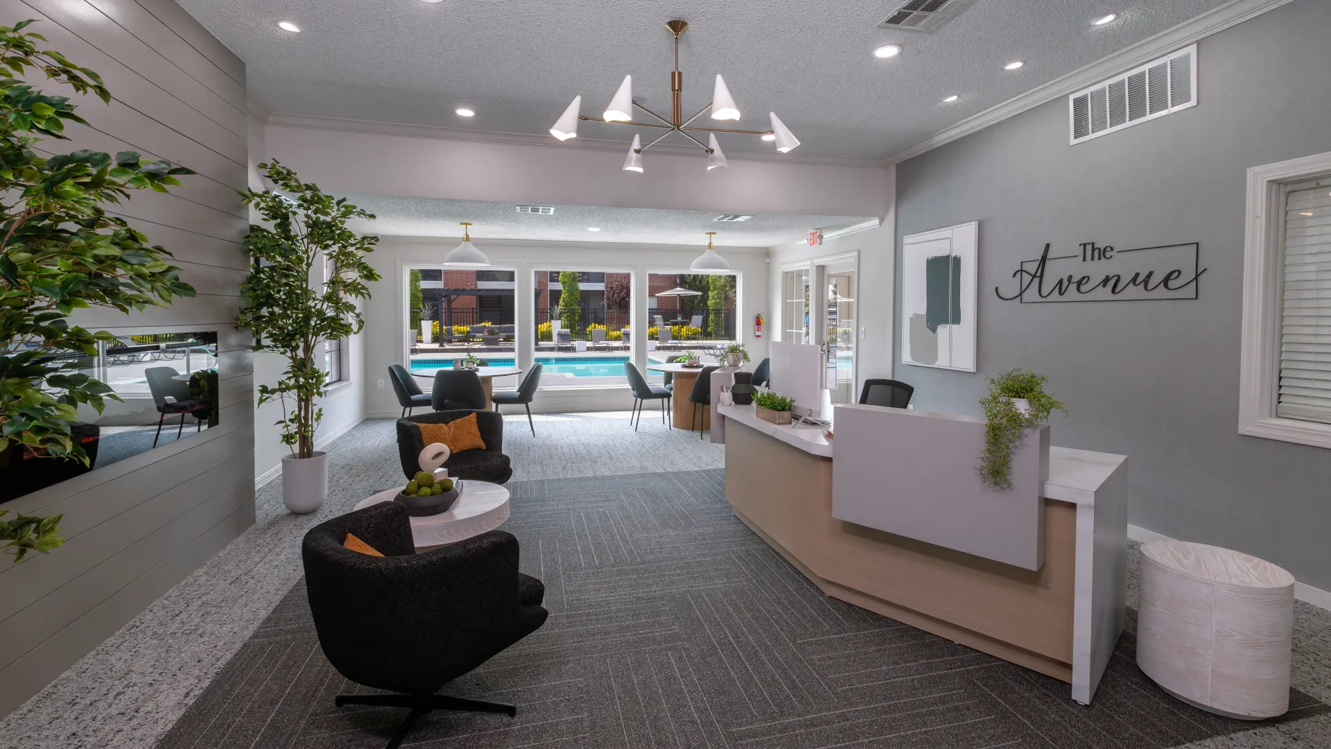 Interior view of The Avenue's leasing office featuring modern decor, comfortable seating, and large windows overlooking the pool area.