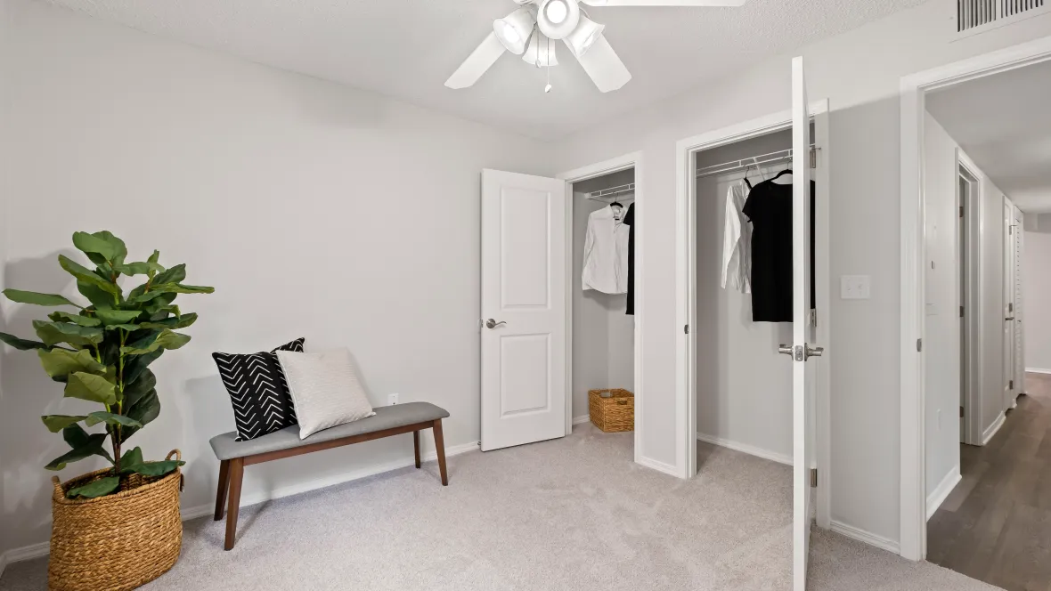 Bright bedroom with overhead lighting and generous double closet space, featuring soft, inviting flooring.