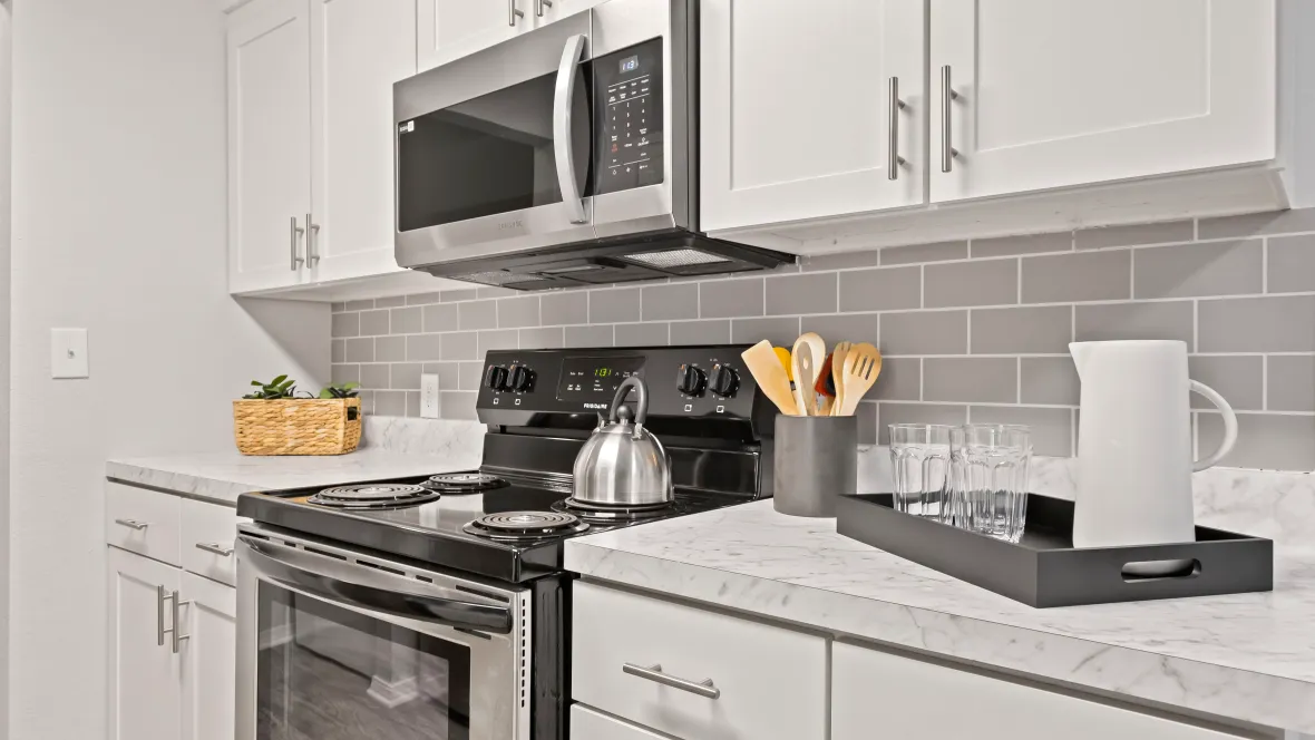 A modern kitchen equipped with sleek, full size stainless steel appliances and a gorgeous, grey subway tile backsplash. 