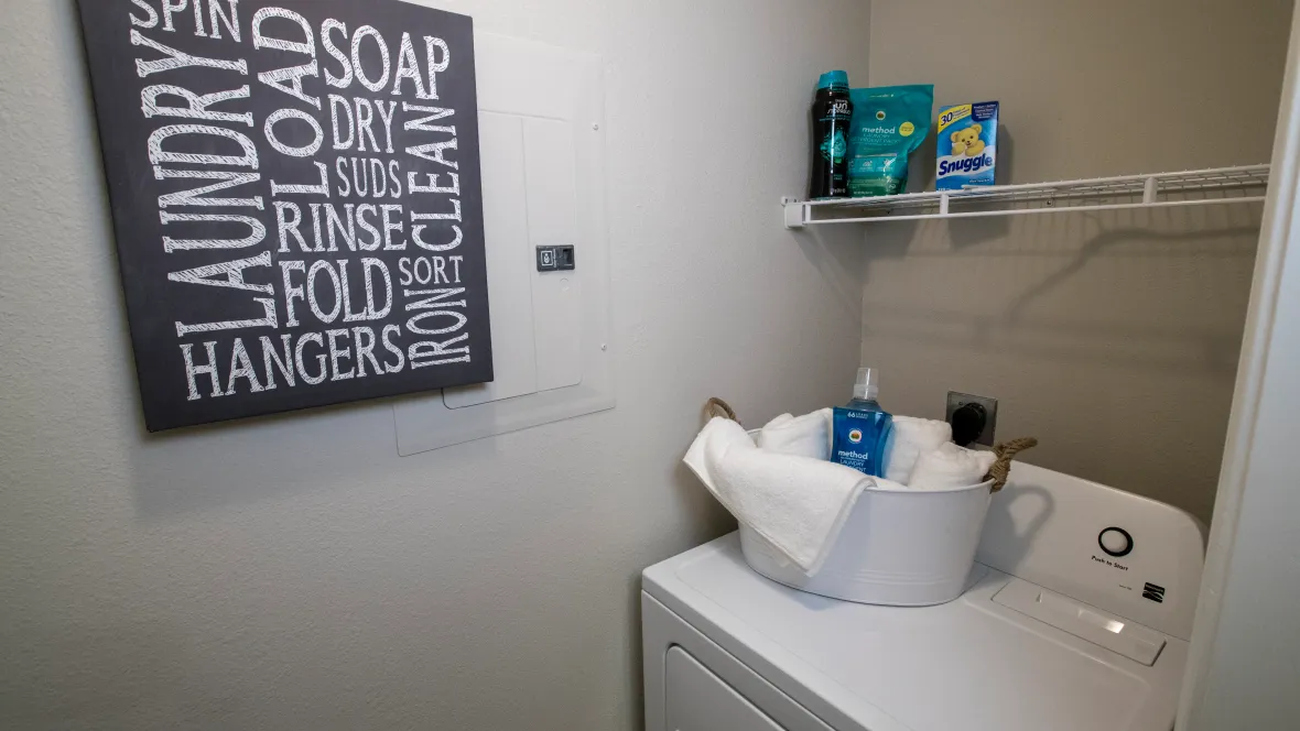 A modern washer and dryer in a spacious laundry room complete with additional shelving above the units. 
