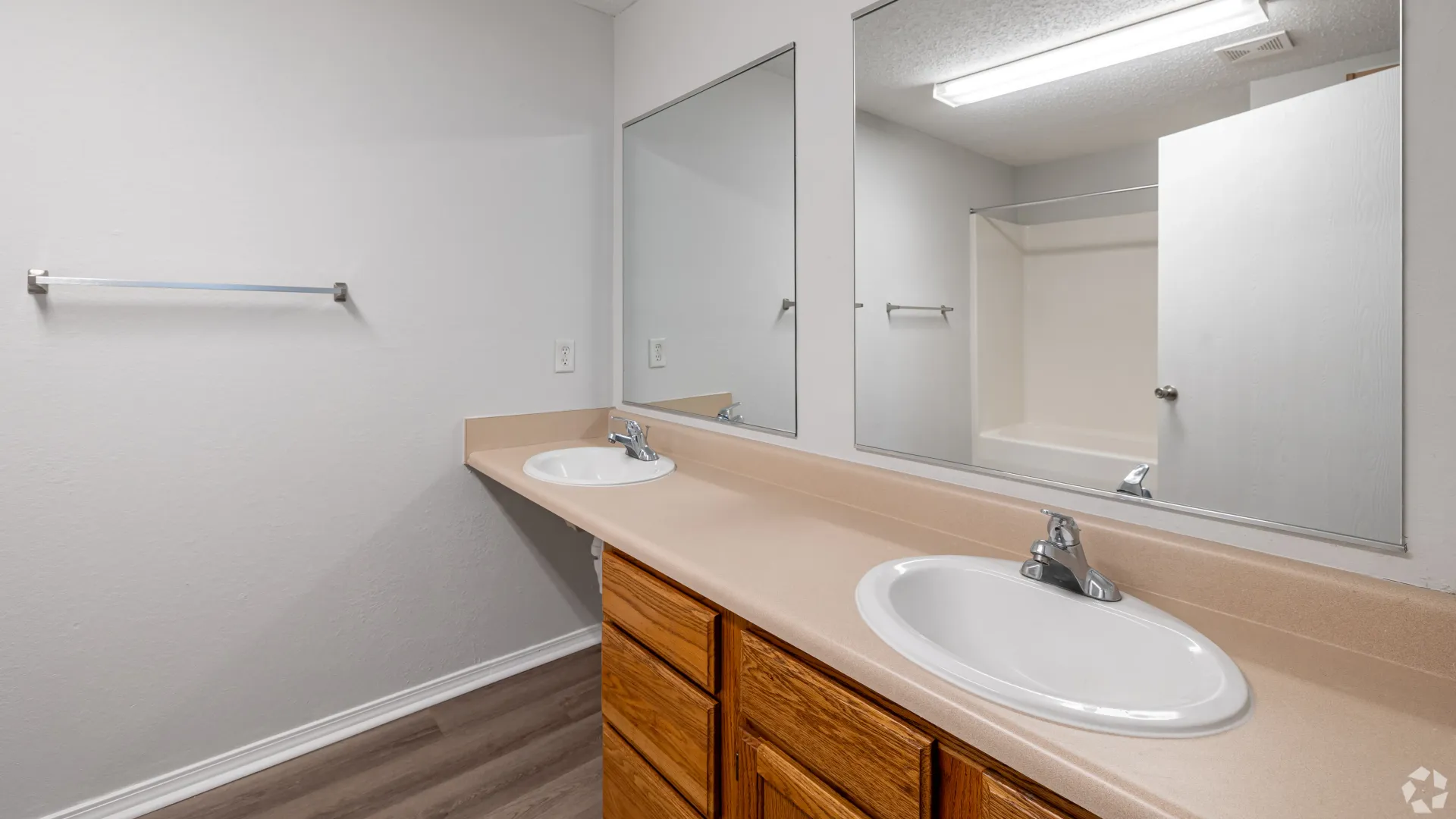 Light-filled bathroom featuring dual vanity with wood cabinets and mirrors above each sink.