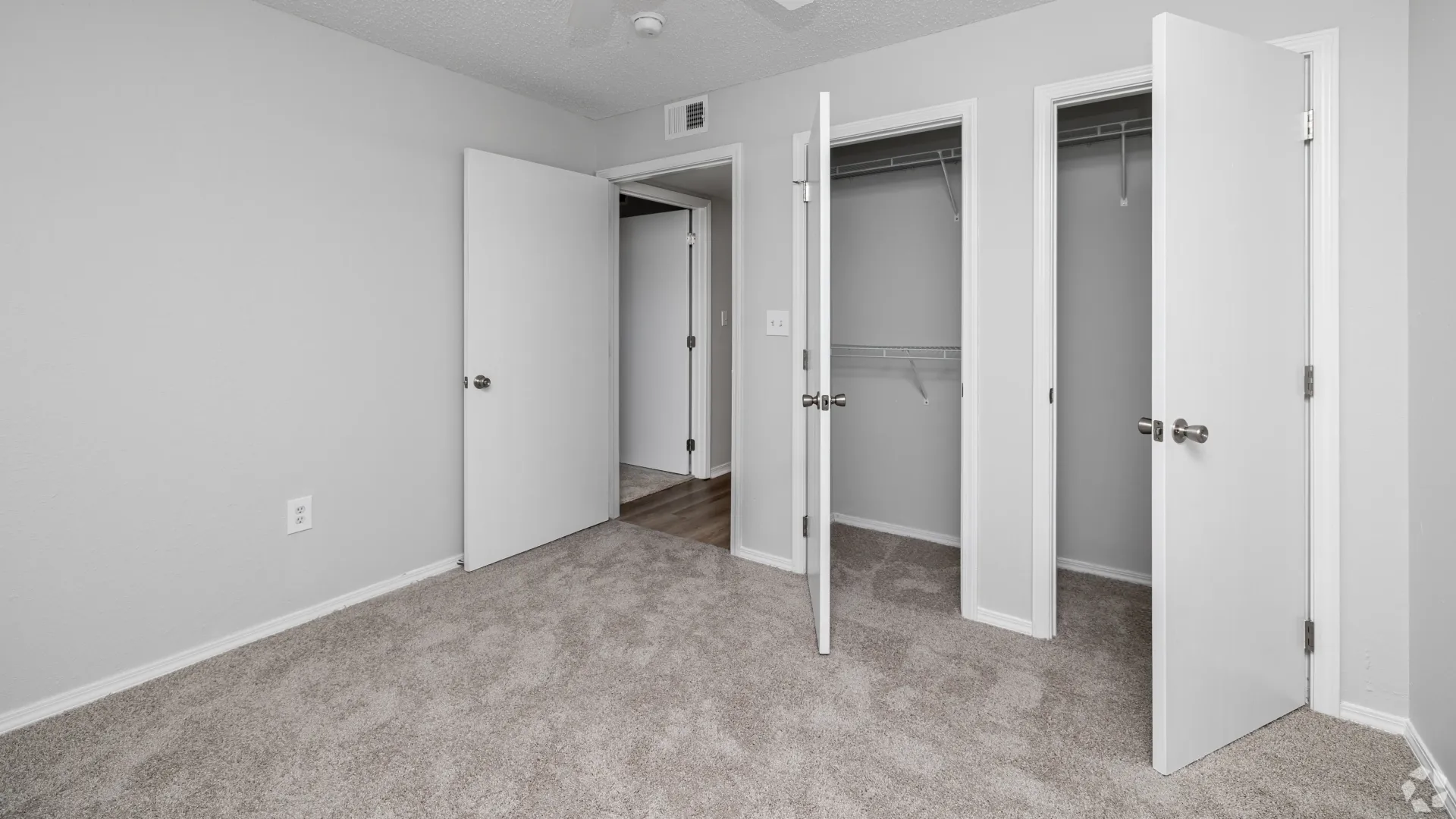 Carpeted bedroom with double closets and white doors at The Avenue.