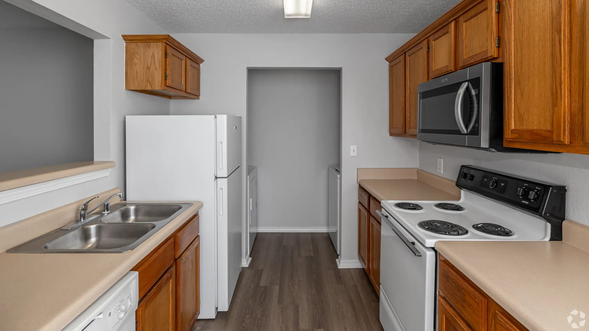 Galley-style kitchen with wood cabinets, white appliances, and laminate countertops.