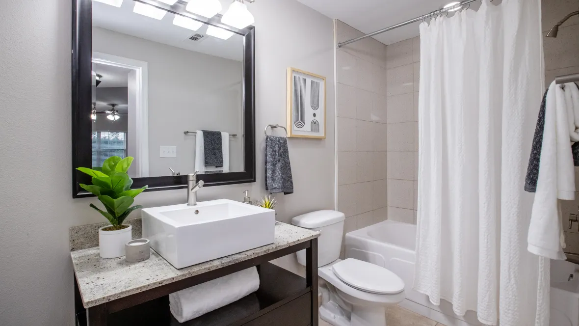  A contemporary guest bathroom with tiled flooring, modern designed sink, and a generously-sized, framed mirror – for sleek sophistication. 