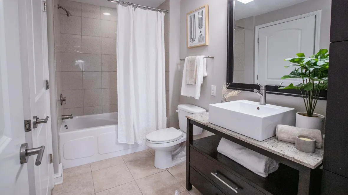 A stylish bathroom with elegant finishes from tile floor, square boutique sink above a granite countertop, and a chic tile tub surround, creating an elegant and functional space.