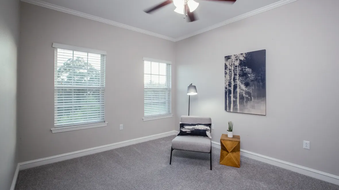 A tranquil guest bedroom featuring a breezy ceiling fan and double split windows for maximized natural lighting.