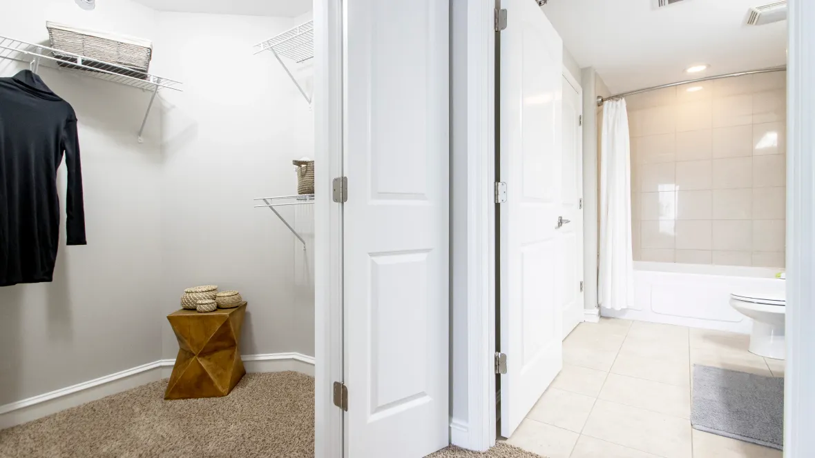 An oversized walk-in closet featuring customized built-in shelving providing ample storage choices and a refined master bathroom with gleaming tiles. 