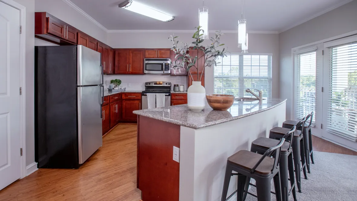 An exceptionally large, chic kitchen featuring cherry wood cabinets and gleaming granite countertops with breakfast bar seating for four, ideal for hosting gatherings and creating lasting memories.