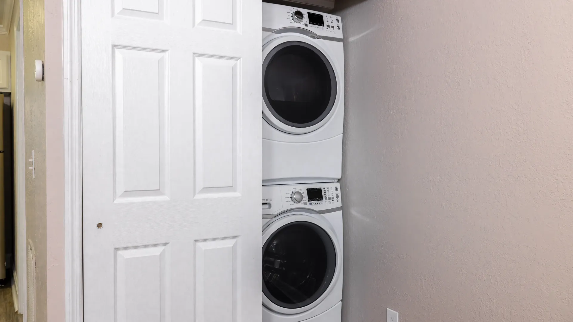 A modern laundry space showcasing stacked, front-loading washer and dryer units discreetly tucked behind a sliding door for a seamless and sleek look.