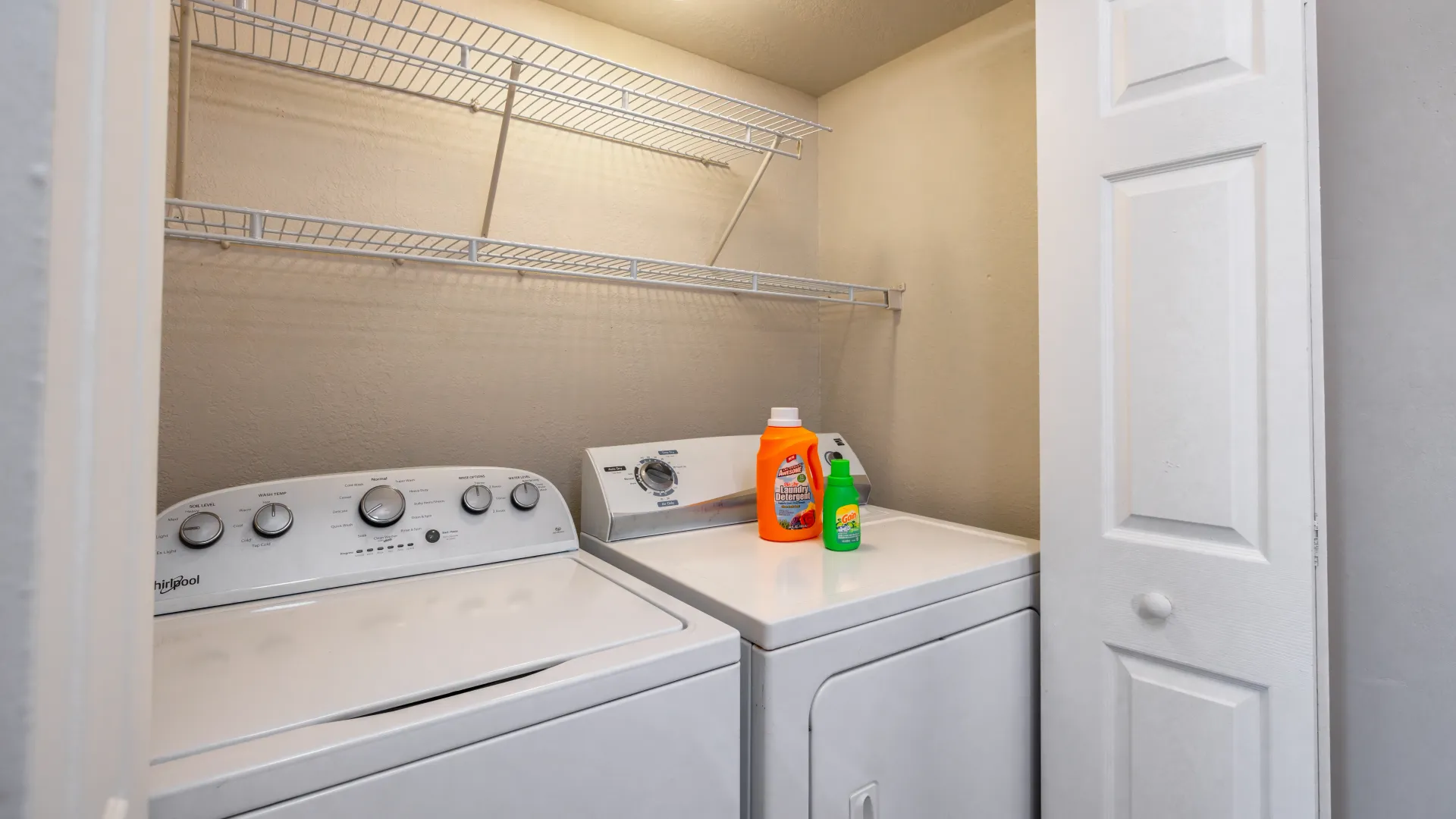 A convenient laundry room adjacent to the kitchen, featuring extra shelving above full-size appliances.
