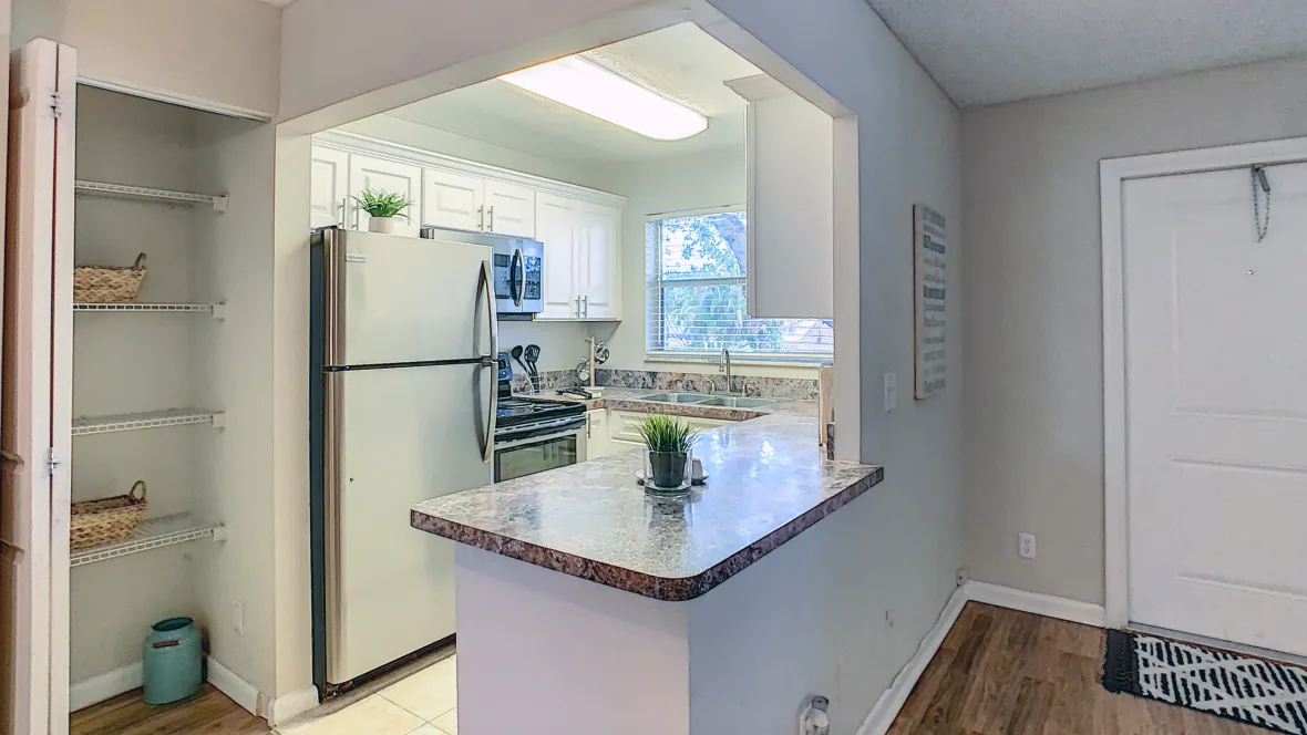 A charming kitchen adorned with a spacious pantry beside gleaming stainless steel appliances—complete with a sprawling countertop, perfect for culinary creations.