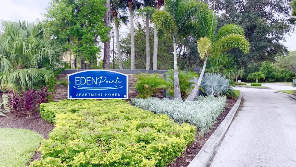 The front entrance of the community, featuring lush, tropical landscaping and a community sign that reads: Eden Pointe Apartment Homes.