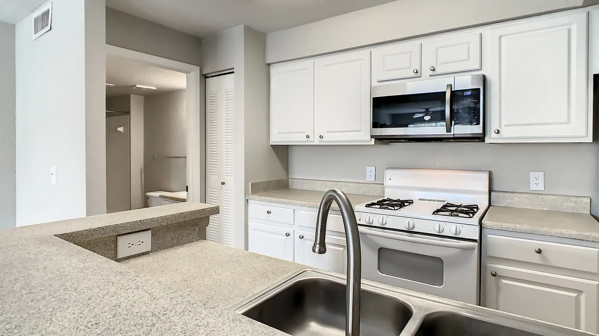 A kitchen with white cabinetry and stainless steel microwave above the stove.