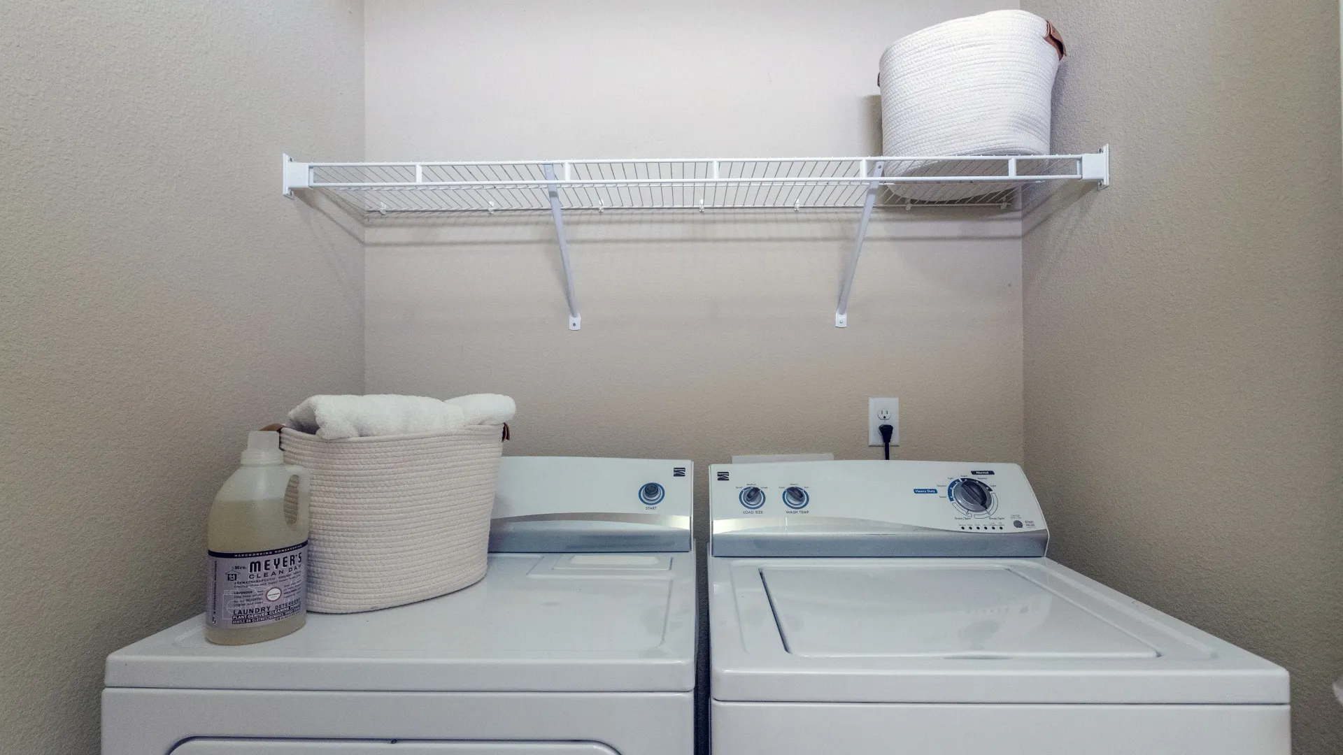 A full-size, side-by-side washer and dryer inside of a laundry closet in an apartment home.