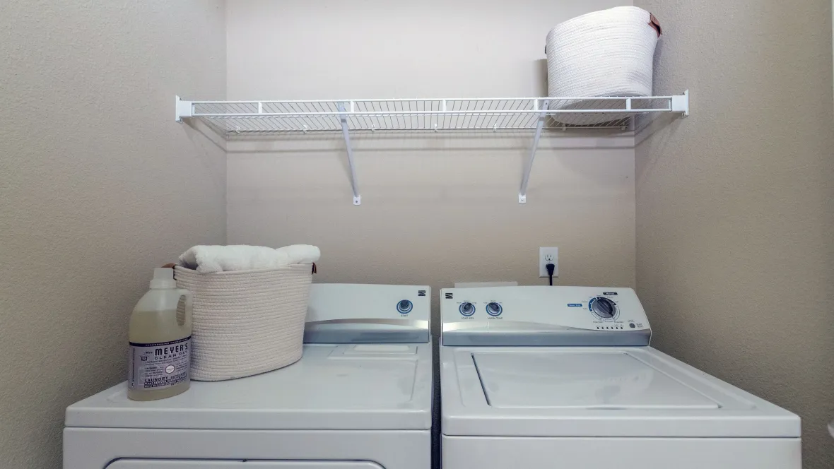 A full-size, side-by-side washer and dryer appliance package inside of a laundry closet in an apartment home.