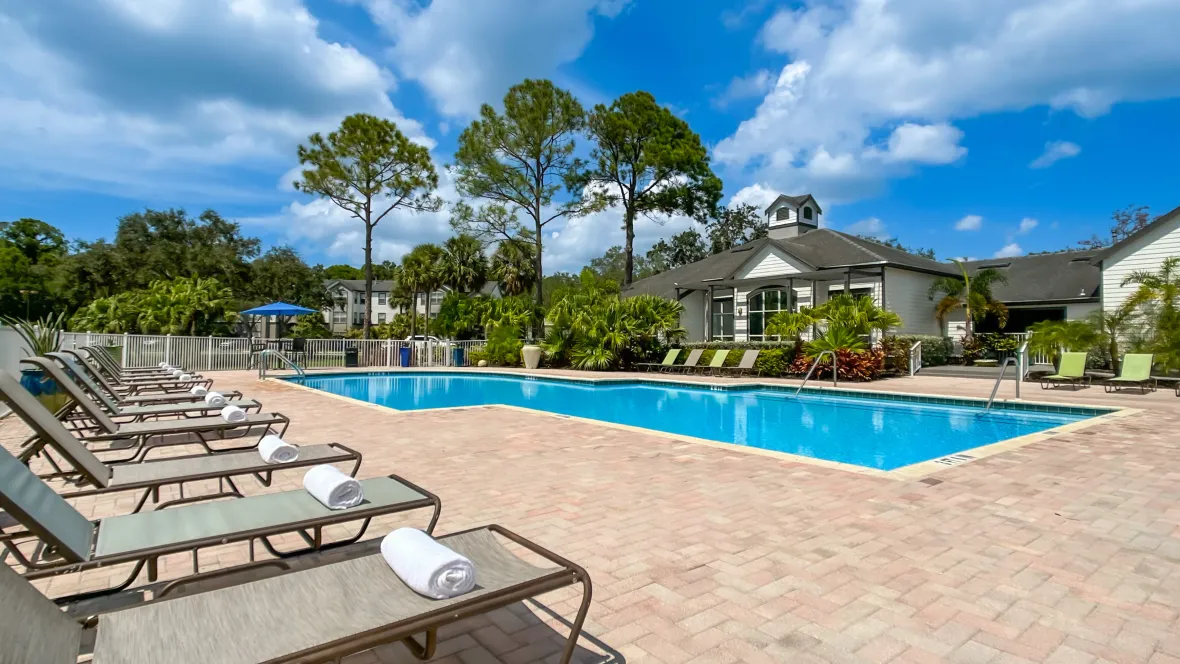 A view of the pool from a row of loungers, with the leasing clubhouse visible in the distance