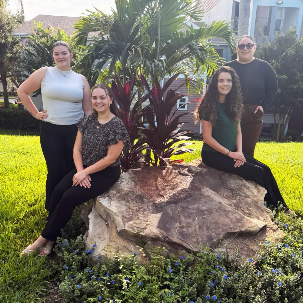 Leasing team members at Ashton Chase posing in a beautifully landscaped outdoor area surrounded by greenery.