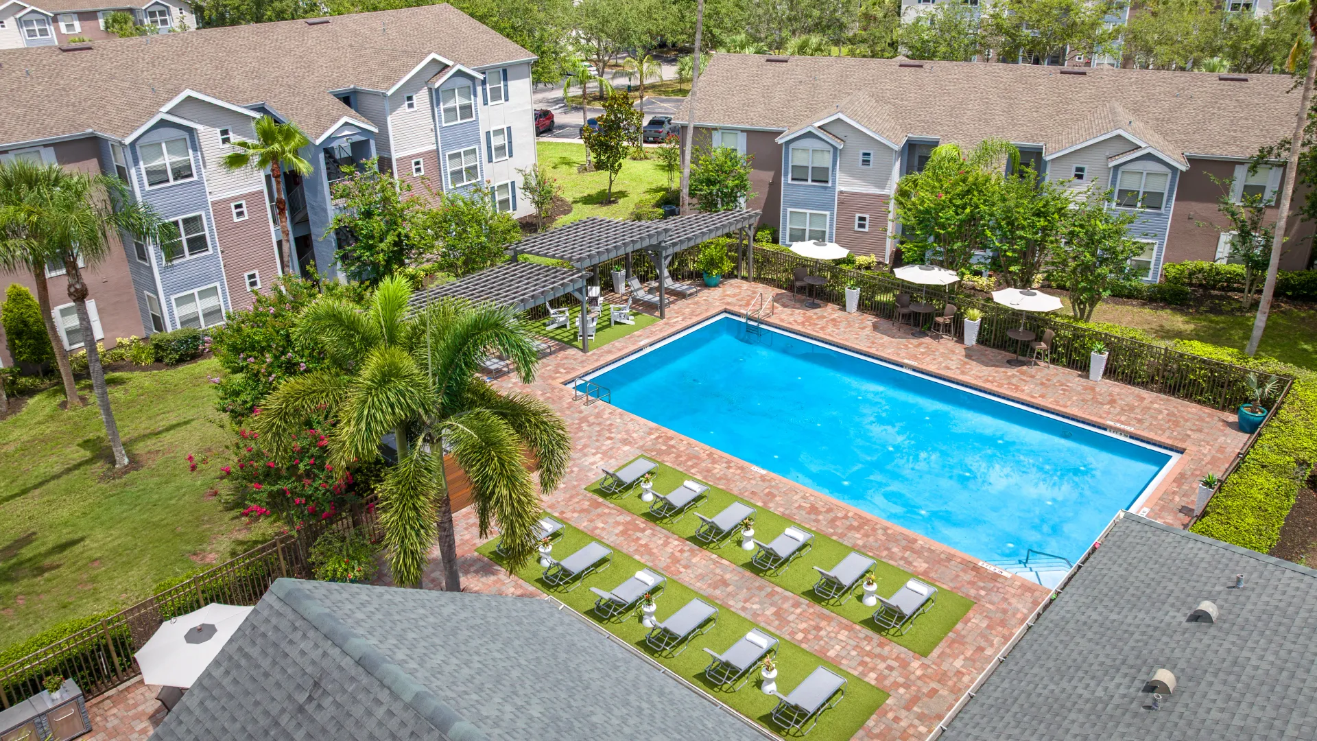 Aerial view of Ashton Chase pool area with lounge chairs, pergola seating, and surrounding landscaping.