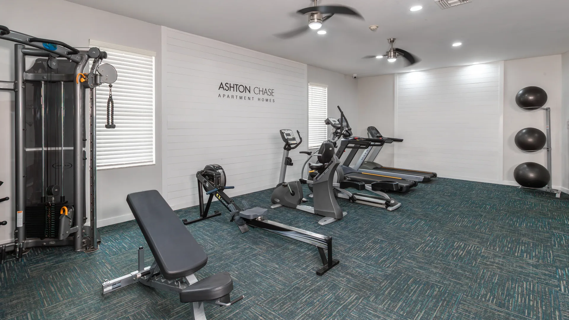 Ashton Chase gym with treadmills, rowing machine, bench press, resistance machine, and exercise balls.