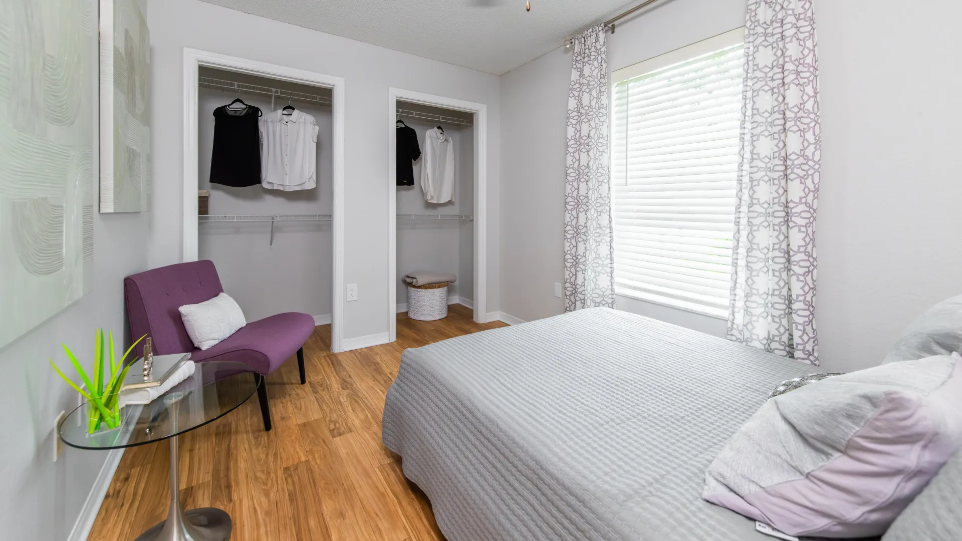 Secondary bedroom at Ashton Chase Apartments with gray bedding, dual closets, and natural light.
