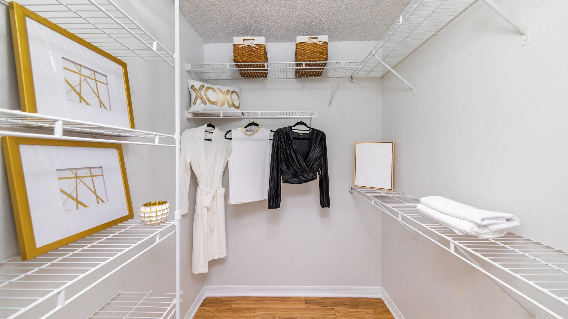Walk-in closet with built-in shelving, hanging clothes, and decorative accents at Ashton Chase Apartments.
