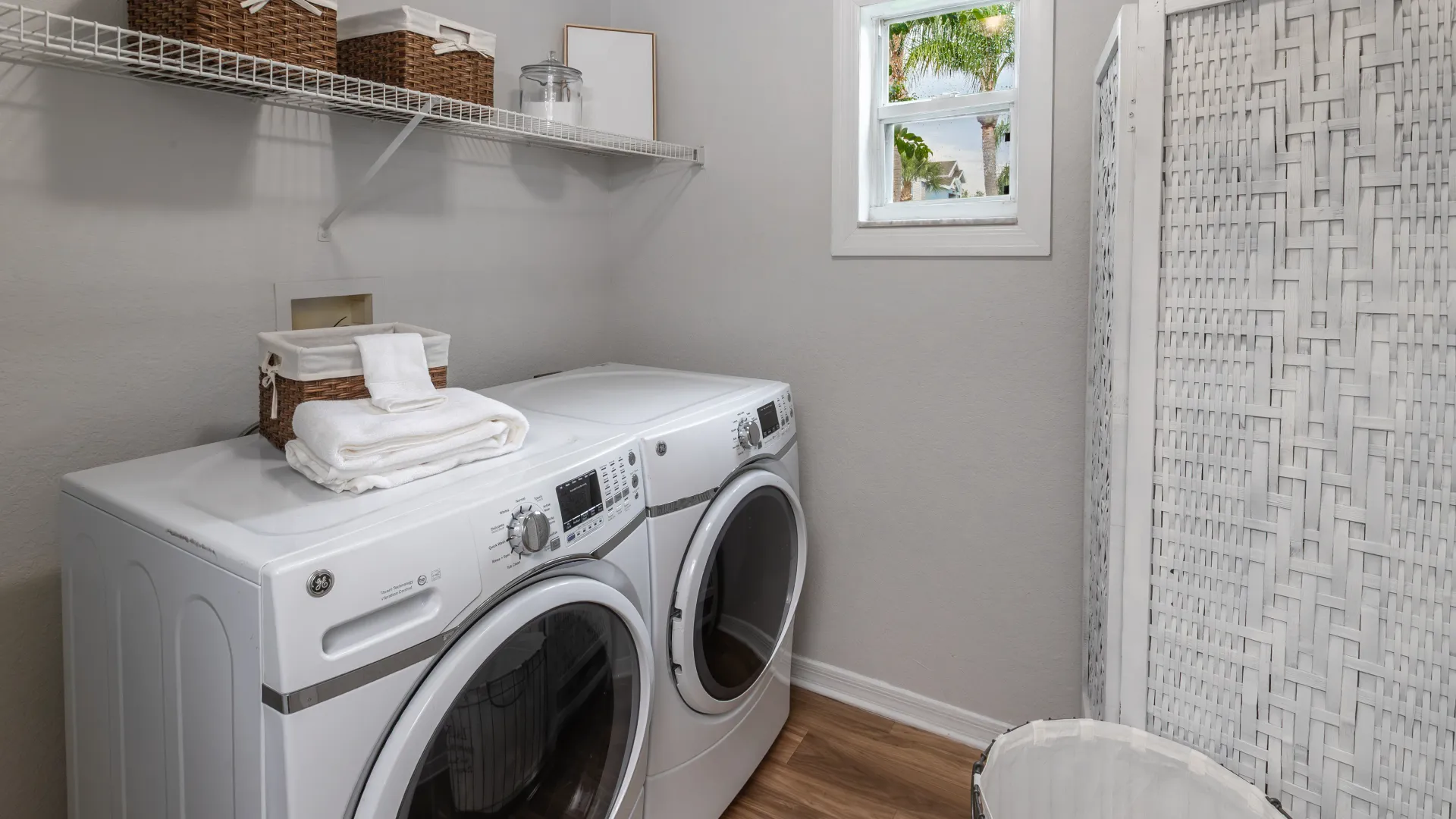 Ashton Chase laundry room featuring a full-size washer and dryer set, overhead shelving, and window.