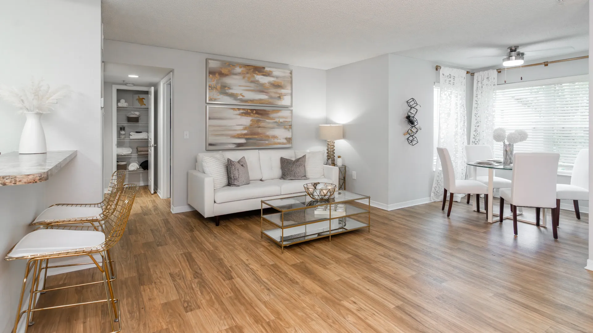 Ashton Chase apartment interior with modern living room, dining area near window, and breakfast bar with gold stools.