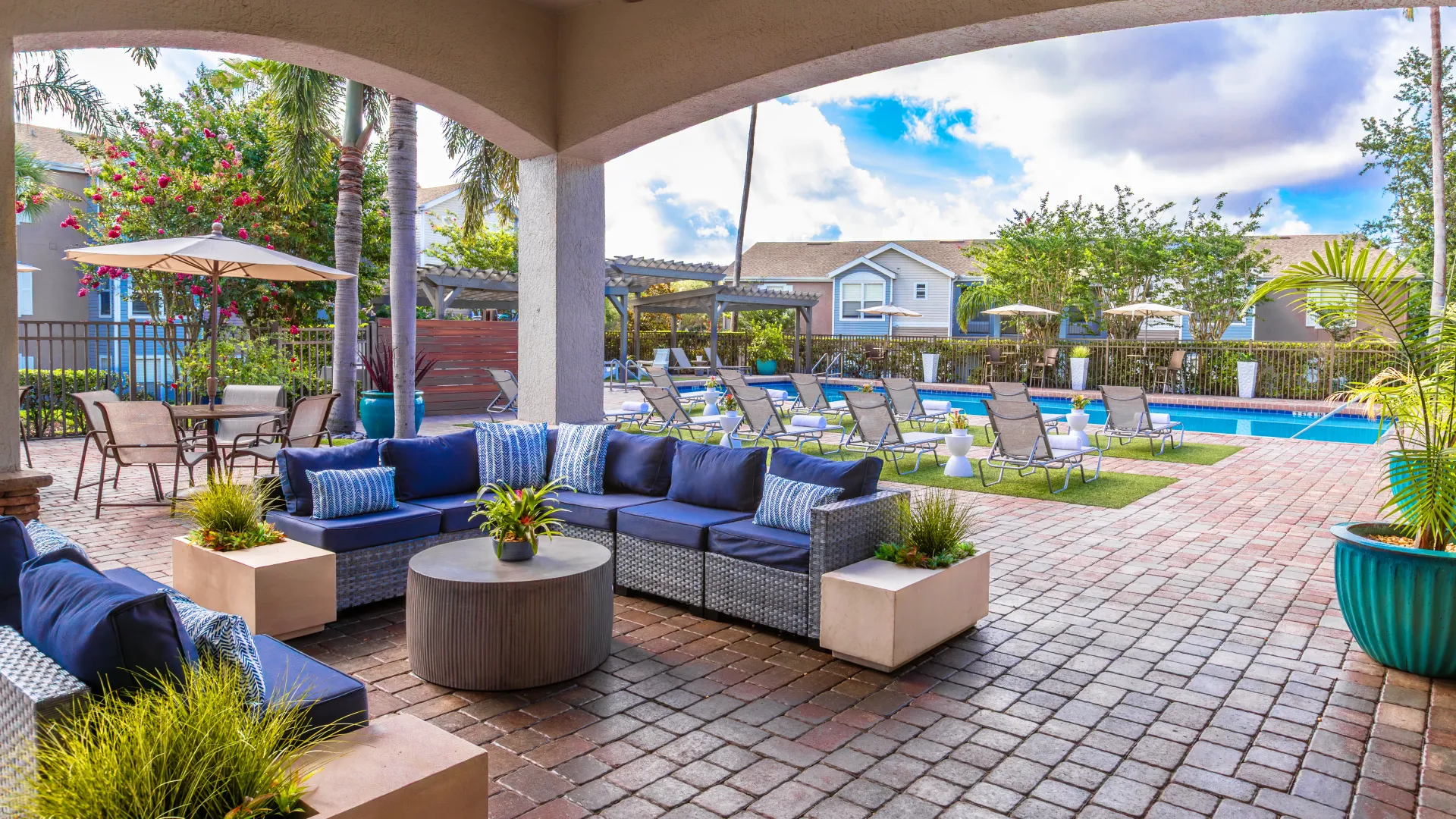 Covered outdoor lounge area with navy cushioned seating and pool view.