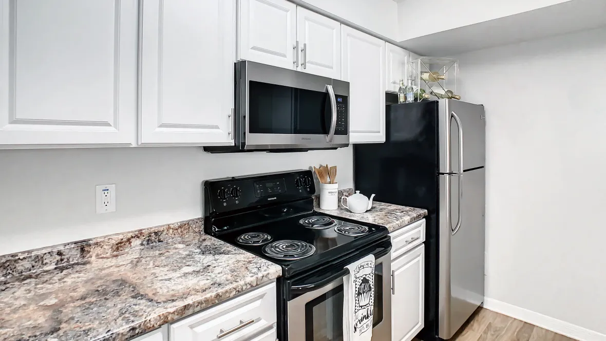 Stylish kitchen with sleek granite-style countertops, pristine white cabinetry, and gleaming stainless steel appliances.