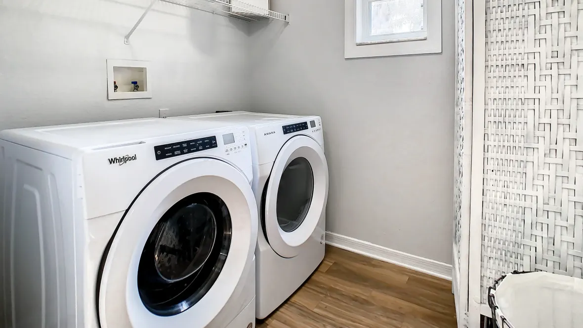 Laundry room with ample natural light, full-size appliances, and a convenient wall-to-wall shelf.